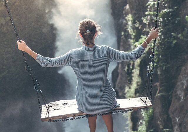 woman on a swing overlooking large waterfall